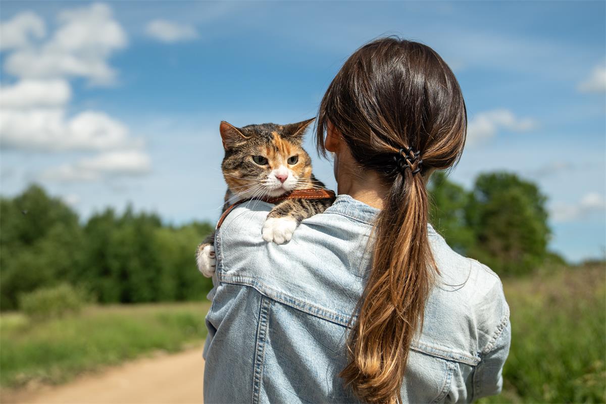 a woman with long hair walking while holding her cat